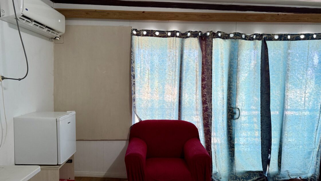 ツバルのフィラモナロッジVIPルームに置かれた赤い1人がけソファと冷蔵庫。