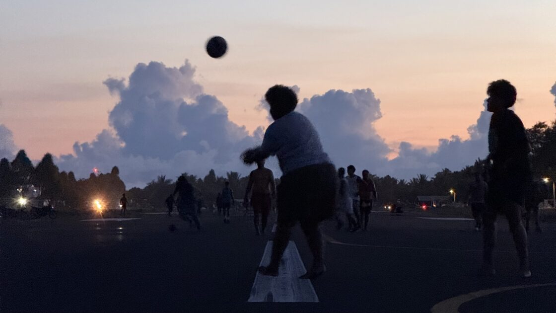 夕方のツバルの滑走路でバレーボールを楽しむ現地の人々のシルエット
