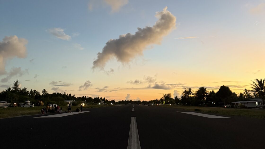 オレンジ色の夕焼け空と雲の下に広がる、ツバルの夕暮れ時の滑走路。