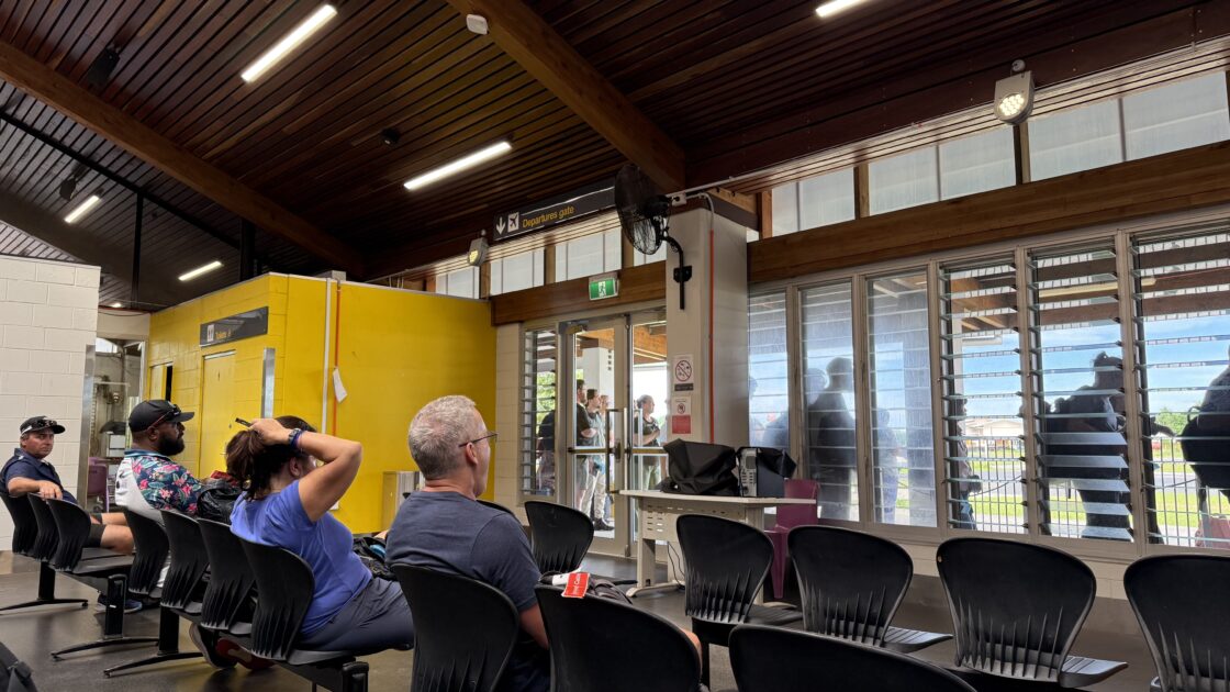 ツバルのフナフティ国際空港の唯一の搭乗口で、椅子に座って出国を待つ人たちの後ろ姿